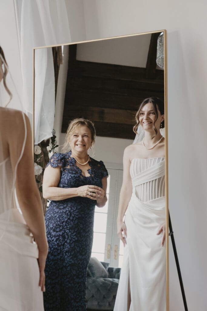 Bride and mother of the bride smiling before ceremony
