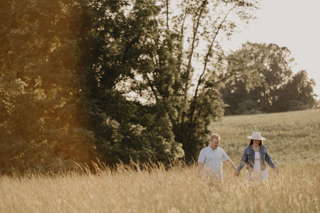 Engaged couple walking in a field at Fair Hill Nature Center 